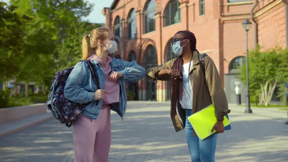 Divirse College Friends in Mask Meeting Outdoors Bumping Elbows Greeting alt