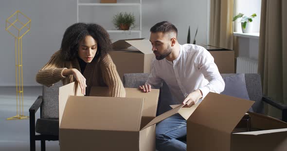 Focused Confused Couple Young Family African American Wife and Caucasian Man Open Unpack Parcel alt