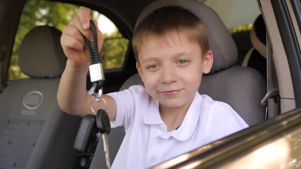 A Little Boy is Sitting in a New Car in the Front Seat with Keys in His Hands alt