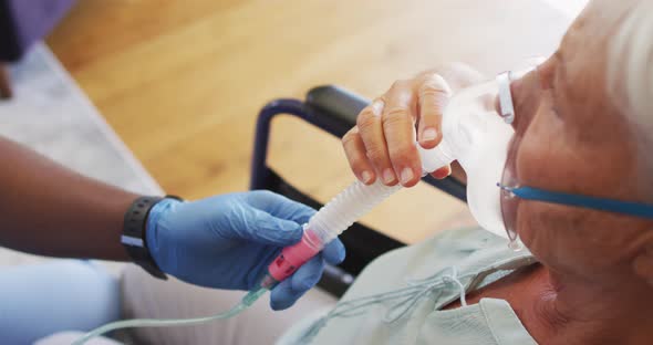 Video of hands of african american male doctor keeping oxygen to caucasian senior woman alt