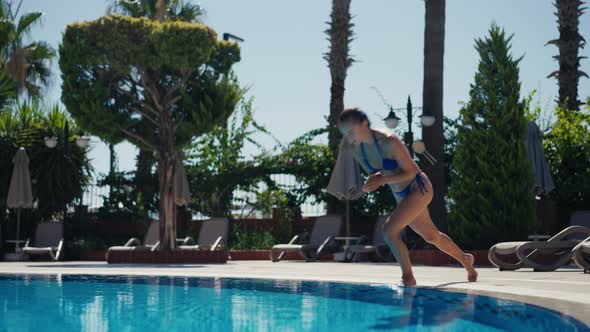 An Active Young Woman in a Swimsuit Dives Into the Pool and Splashes Glassy Water alt