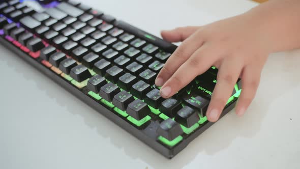 Little boy hand playing game with RGB keyboard. Close up.