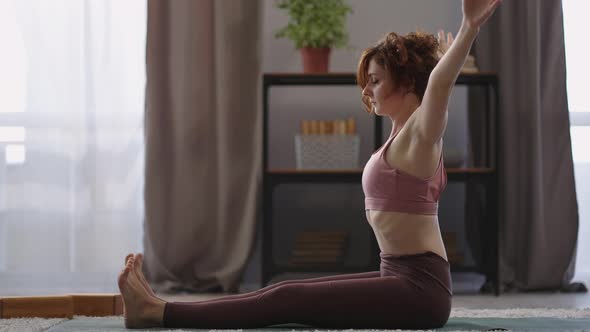 Woman is Sitting in Lotus Position on Floor in Apartment Doing Exercises for Stretching Side View on alt