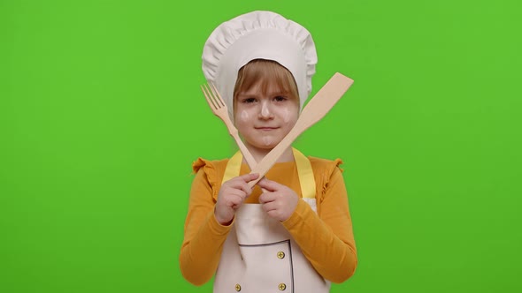 Child Girl Kid Dressed As Cook Chef with Fork and Spatula Showing Symbol of Rejection Disagreement alt