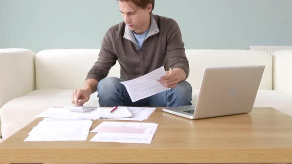 Worried young man doing paperwork alt
