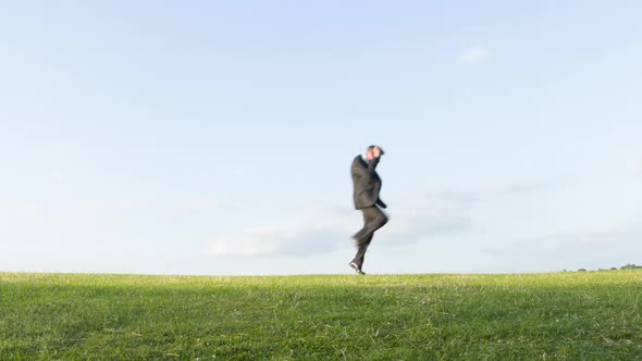 Crazy businessman dancing on a hill