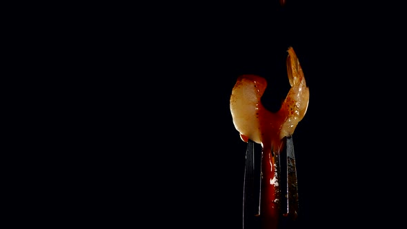 freshly cooked juicy shrimp on a fork poured with tomato sauce on a black background. healthy food alt