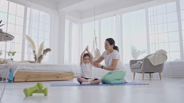Caring Mom Helping Little Girl to Keep Yoga Pose alt