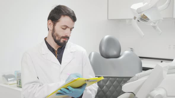 Professional Dentist Filling Medical Documents at His Office alt