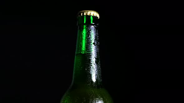 A Cold Beer Bottle in the Dark is Illuminated By Light