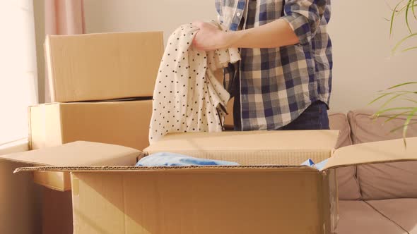 A Woman in a Plaid Shirt Prepares Clothes for the Move