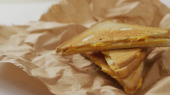 Video of close up of toasted cheese sandwiches on brown paper over grey background alt