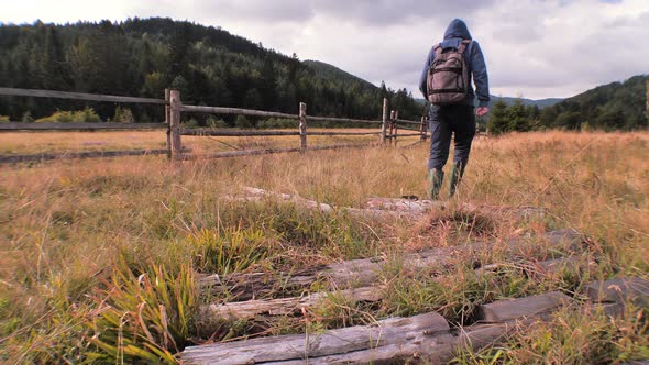 Man in work boots going through field of grass. Mans legs stepping on grass. Carpathians alt