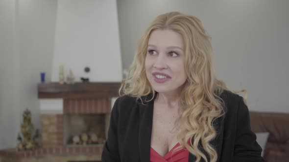 Portrait of Adorable Blond Woman with Curly Hair in Formal Wear Talking in Front of the Camera alt