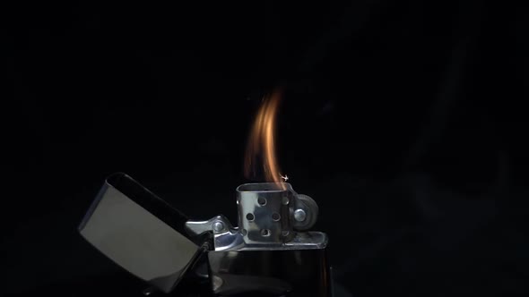 Cigarette Lighter Is Ignited By The Finger On Black Background. Slow Mo