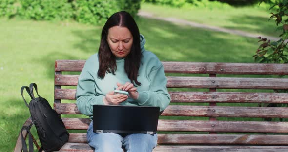 Woman Entrepreneur Is Working Using Phone And Laptop Outdoors In Park