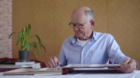 Cheerful Elderly Man Enjoying Memory of Family Photo Album, Watching Old Photos alt