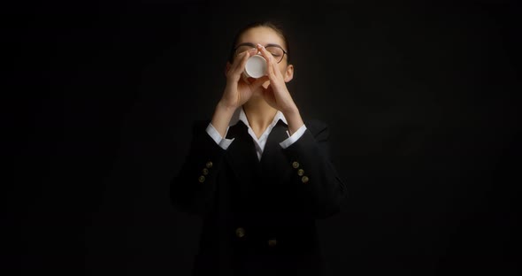 Brunette in Glasses and Office Clothes Drinks Coffee From a White Paper Cup alt