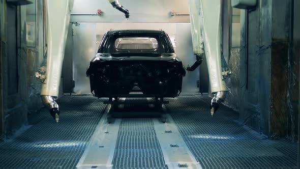 Robots Spray Painting a Car Body Black at a Car Production Factory alt