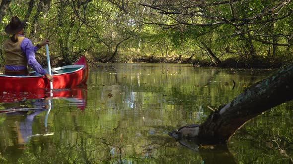 Cowboy in a Canoe Floats on the River in the Forest alt