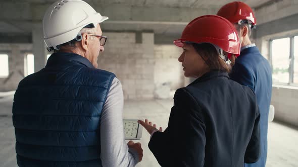 Back view video of caucasian group of walking engineers and investors on construction site. alt