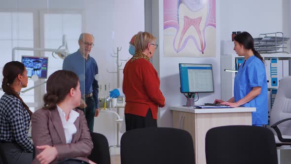 Dentistry Doctor Talking with Senior Woman Standing in Reception Area alt