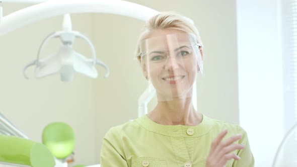 Female Dentist Dressing Up Safety Glasses. Woman Doctor Preparing for Work alt