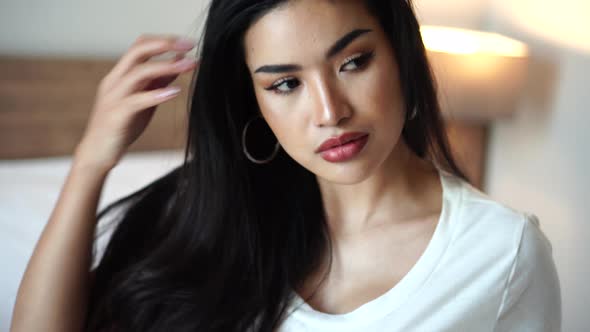 Portrait of Attractive Asian Female Model With Long Hair Posing to Camera in Bed alt