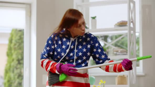Active Funny Mature Woman Imitating Guitar Playing on Broom Cleaning House alt