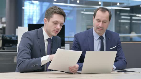 Business People Working on Laptop with Documents in Office alt