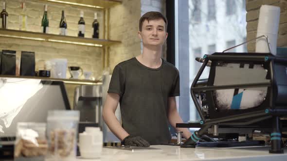 Confident Young Caucasian Barista Posing at Coffee Machine in Cafe alt
