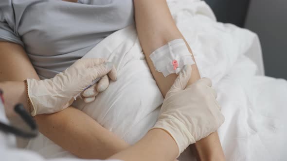 Nurse Putting a Drip Into the Catheter Lying Patients Closeup