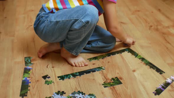 Closeup of a Playing Child Sitting on the Floor and Collecting Puzzles