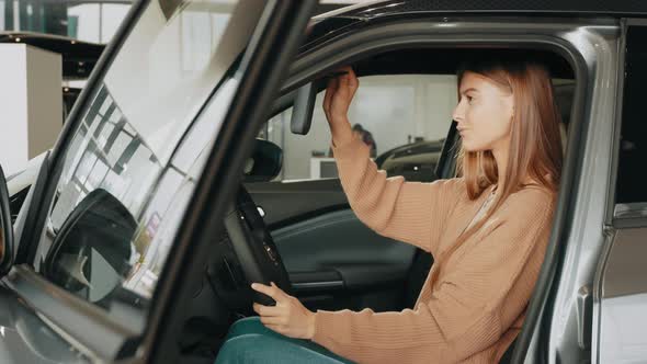 Closeup of Happy Brunette Female Testing Buying Car From Inside During Visit alt