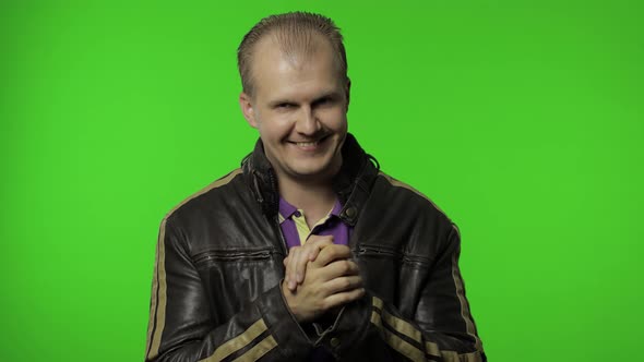 Rocker Man in Brown Denim Jacket Rubbing Hands and Plotting Cunning Idea. Planning Prank alt