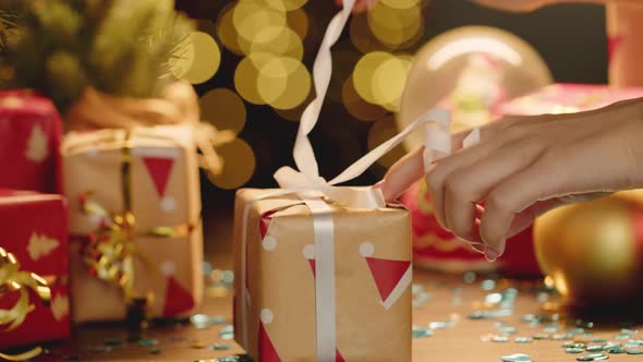 Female Hands Unwrapping Small Christmas Gift Close Up