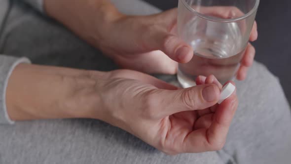 Close-up of a Woman Holding a Magnesium Pill and a Glass of Water