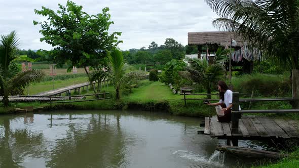 A woman feeding fish in a pond