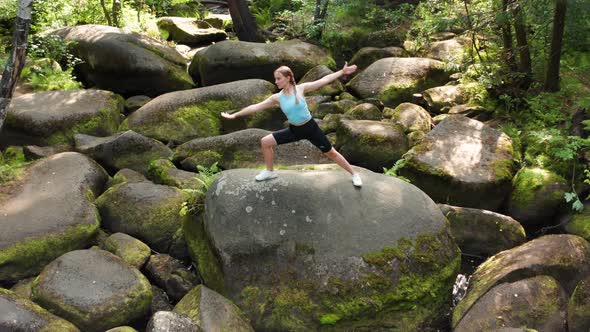 A Girl Does Yoga in the Forest on a Big Stone alt