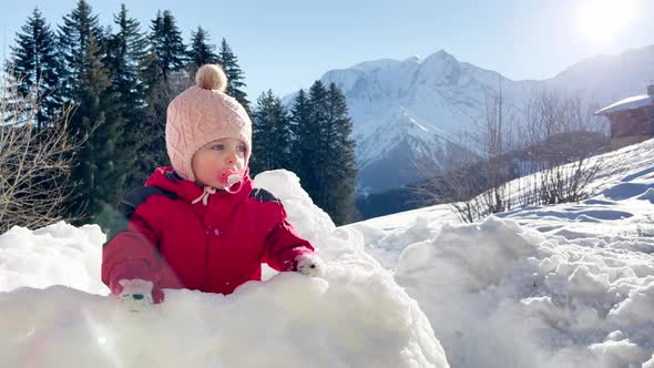 Baby Girl Play in the Snow Fortress with Mountain on Back alt