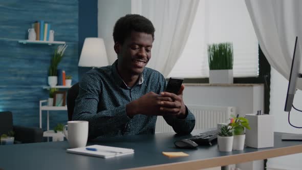 Positive Authentic Black African American Man Smiling While Using a Smartphone alt
