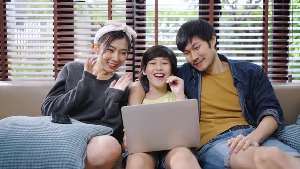 Family smiling talking at camera on laptop.