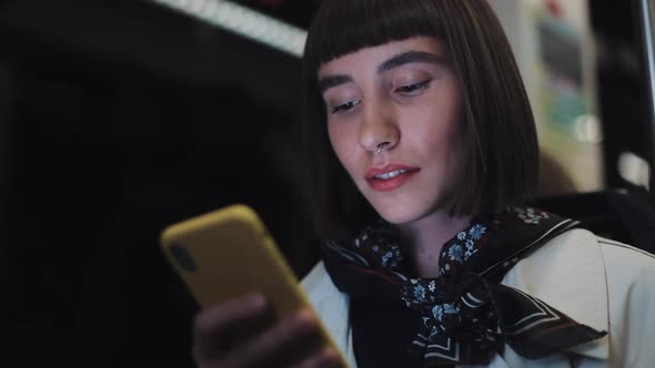 Young Hipster Woman Using Smartphone Sitting in Public Transport, Steadicam Shot. Slow Motion. City alt