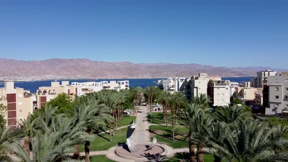 Aerial rising forward drone shot of a palm trees boulevard crossing Eilat city all the way to the de alt