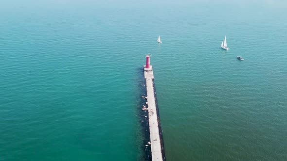 Aerial view of lake Michigan, drone flying around sailboats and lighthouse	