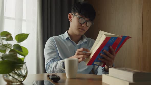 Young Attractive Asian Vietnamese Man is Busy Working Learning on Desk Book at Home Data Analyst alt