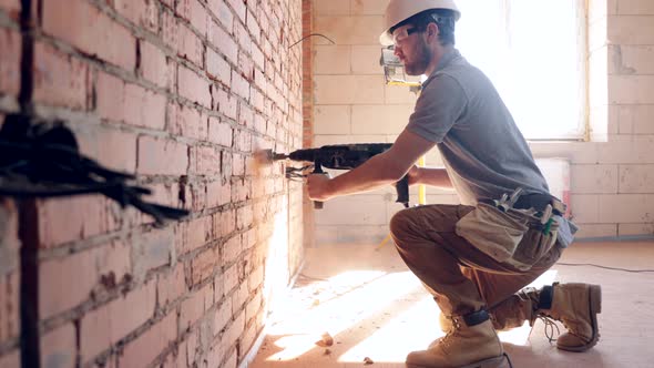 A construction worker works with a puncher close up. alt