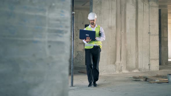 Constructor, Engineer with a Laptop Walks in a Building, Close Up alt