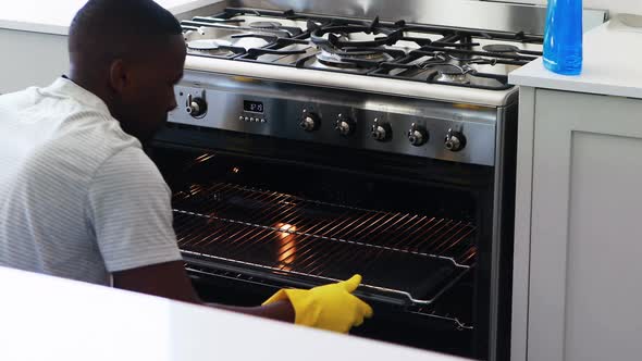 Man cleaning the oven in kitchen alt
