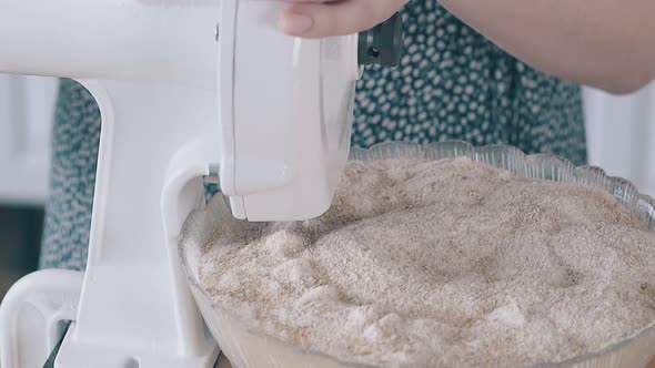 Woman Turns Handle of Domestic Flour Grinder To in Kitchen alt